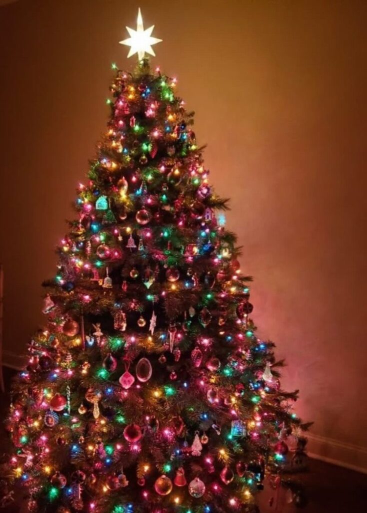 Decorated Christmas tree with colorful lights and a glowing star on top.
