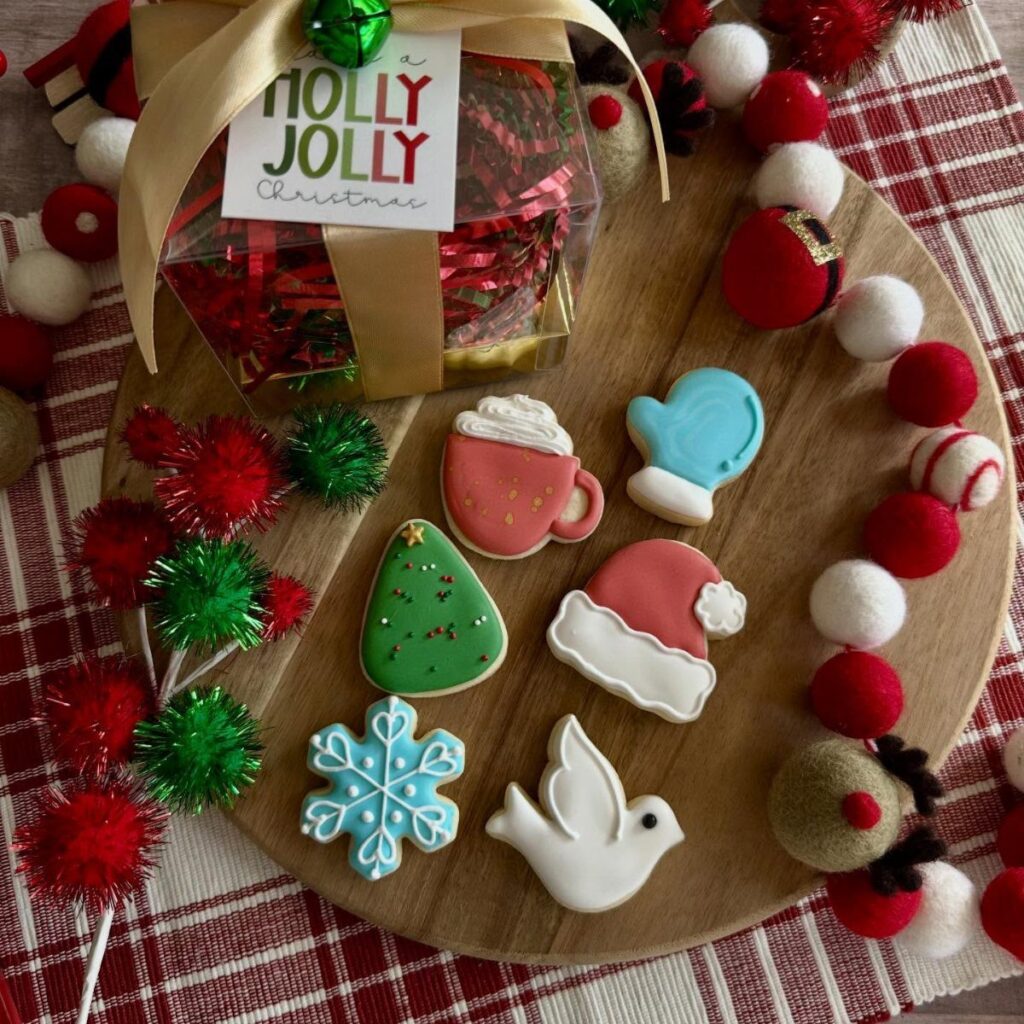 Christmas gift set with decorated sugar cookies and a wrapped present on wooden platter