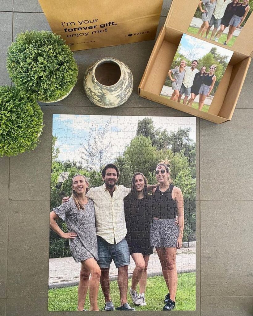 Completed photo puzzle of a family standing outdoors next to its packaging.