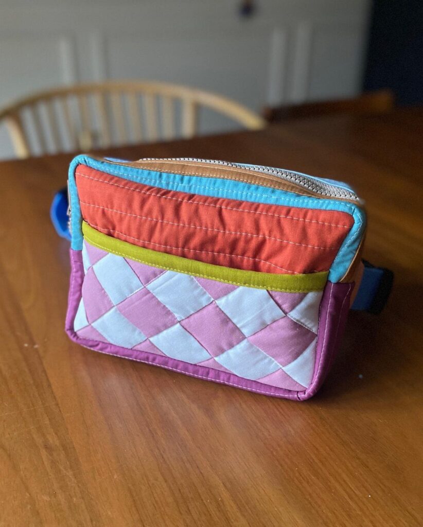 Colorful quilted belt bag with red, green, and pink diamond patterns on wooden table