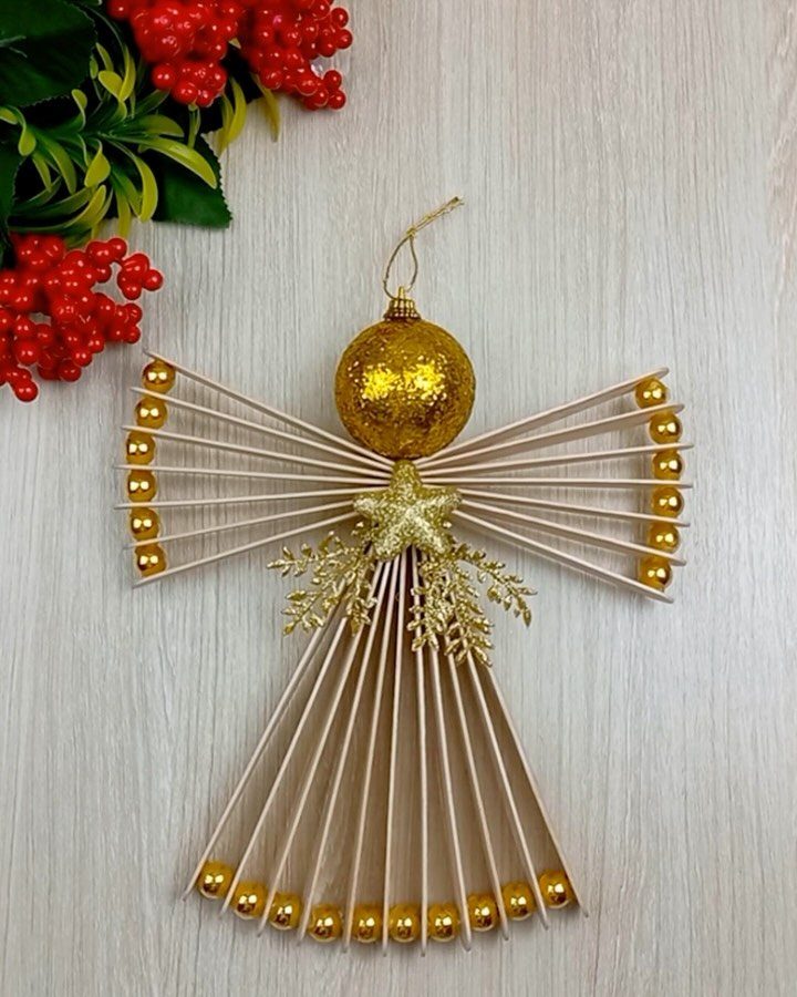 Handmade angel ornament made from wooden skewers and gold beads on white wood.