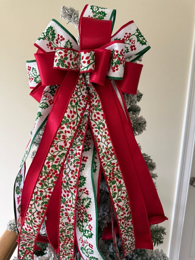 Multi-loop red and white patterned bow topping a frosted Christmas tree