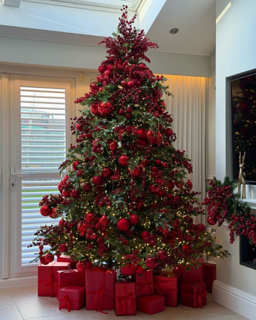 Decorated Christmas tree with red ornaments and lights surrounded by red gift boxes.