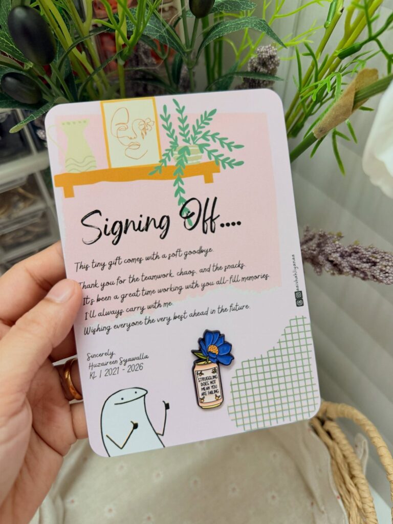 Farewell card with handwritten message and a blue flower pin held by hand.