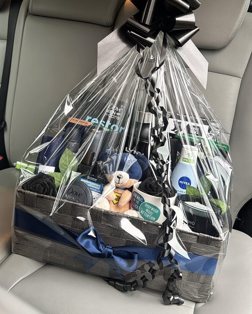 Gift basket with toiletries and a blue teddy bear wrapped in cellophane.