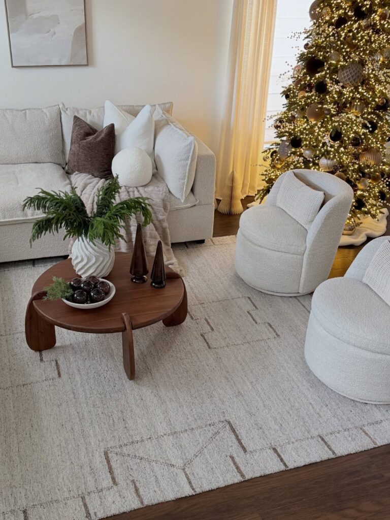 Neutral living room featuring a lit Christmas tree and cream-colored furniture.