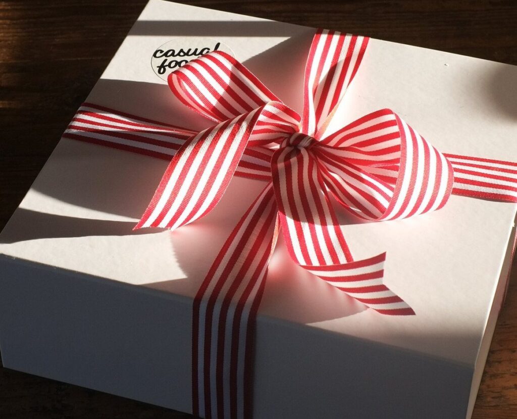 White gift box tied with a red and white striped ribbon bow.