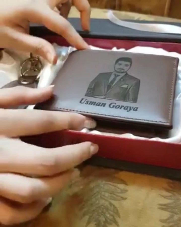 Brown leather wallet with engraved portrait and name inside a gift box.